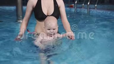 小幼儿不怕在健身中心的水池里学游泳.. 妈妈教儿子在游泳池里游泳。